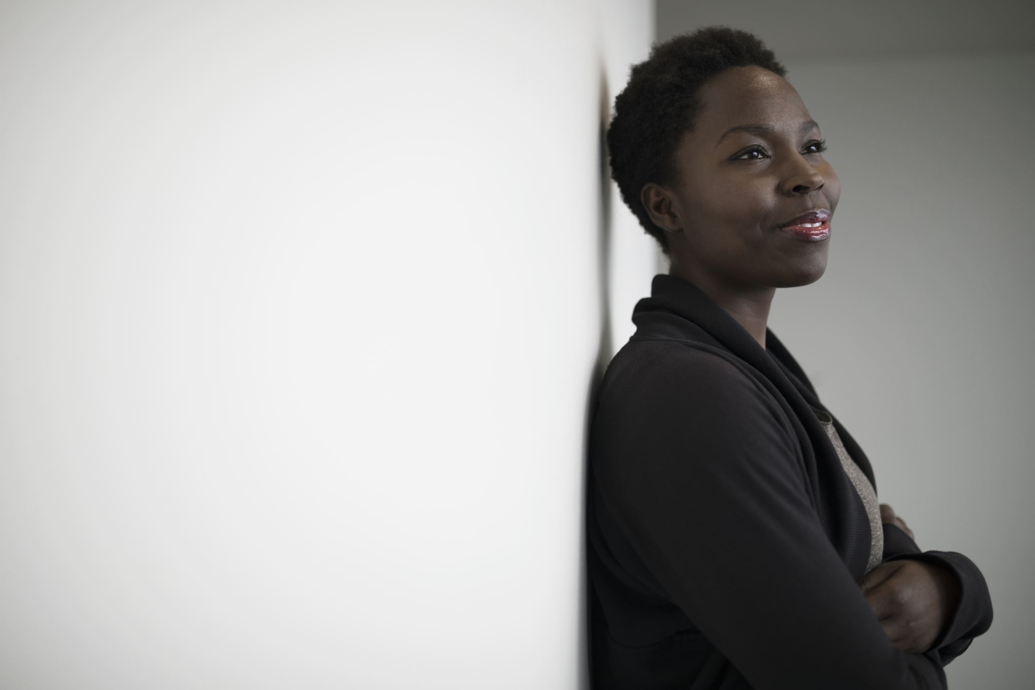 Woman-leaning-against-white-wall-smiling